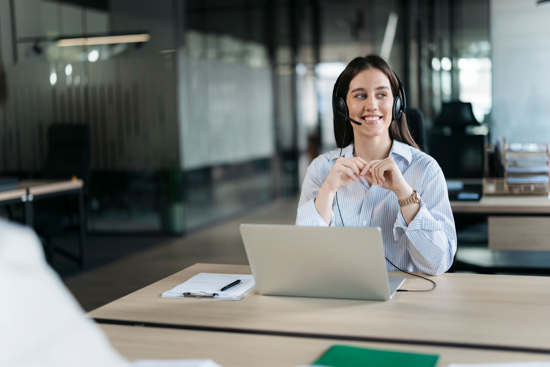 Smiling customer service representative working on laptop in modern office